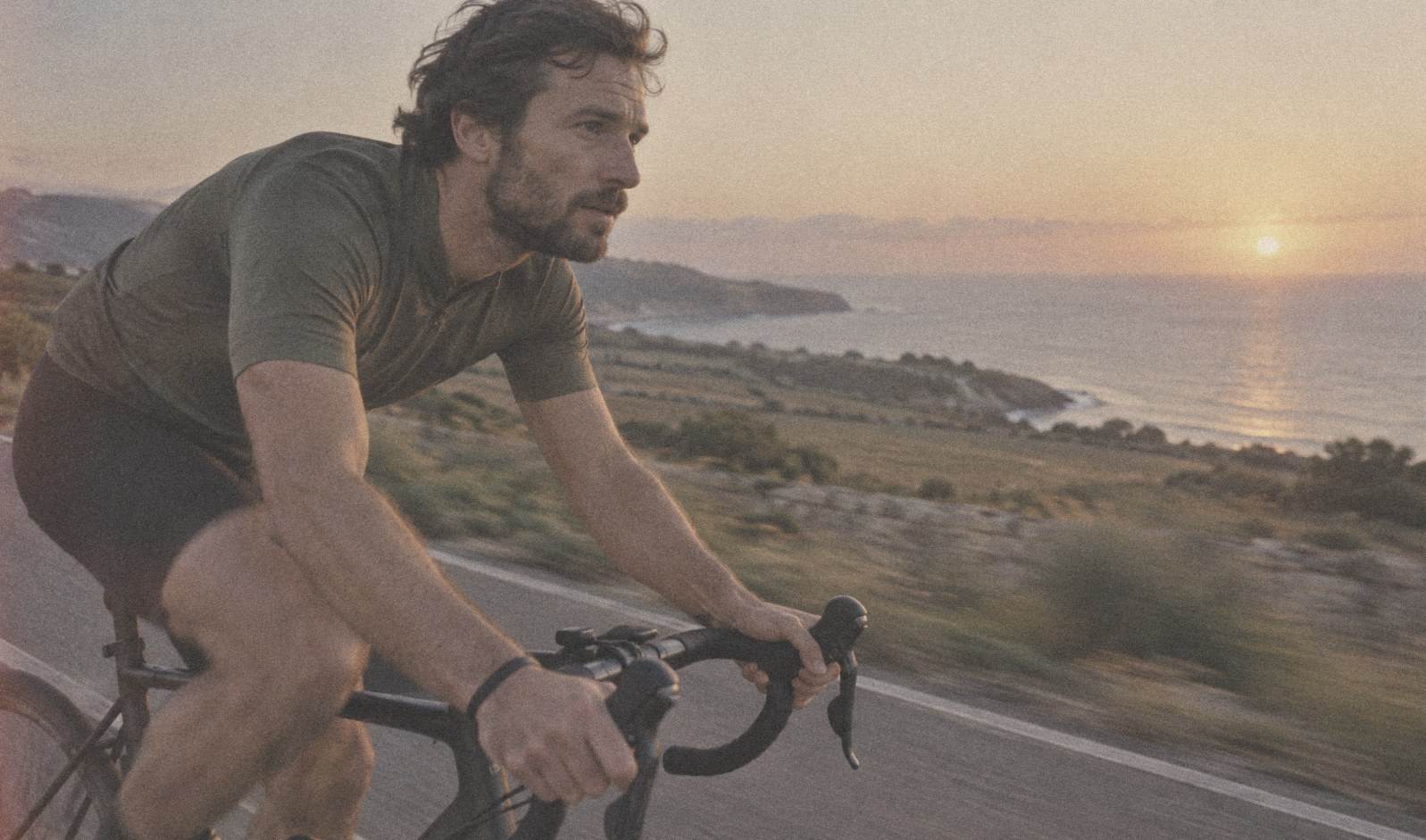 A cyclist on a coastal road at golden hour