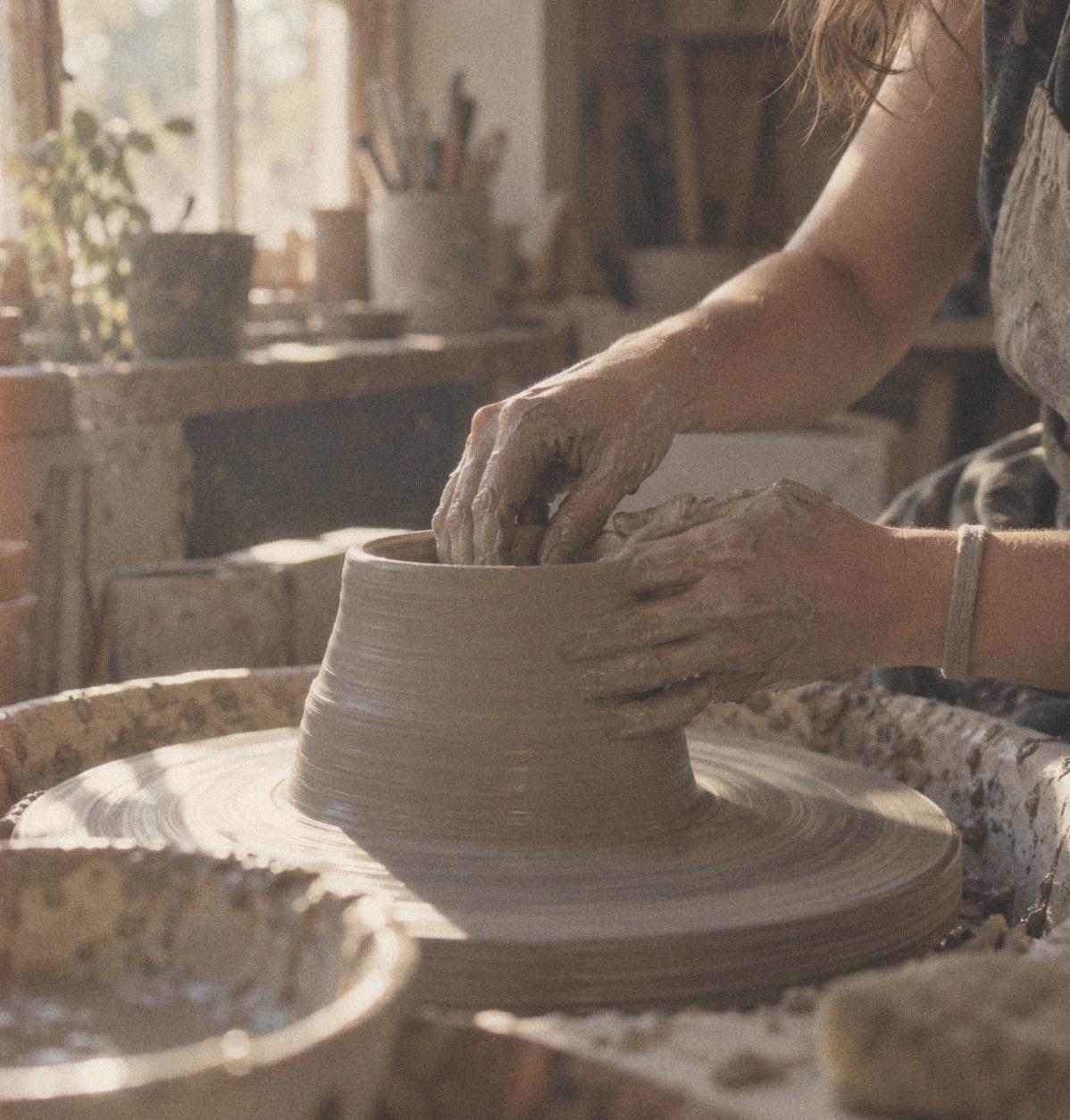 Hands shaping clay on a pottery wheel